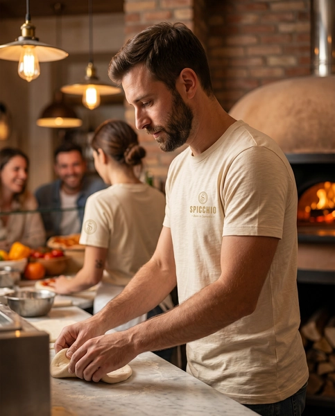 A Spicchio csapata egységes, márkázott pólóban és kötényben pizzatésztát készít egy modern látványkonyhában.
